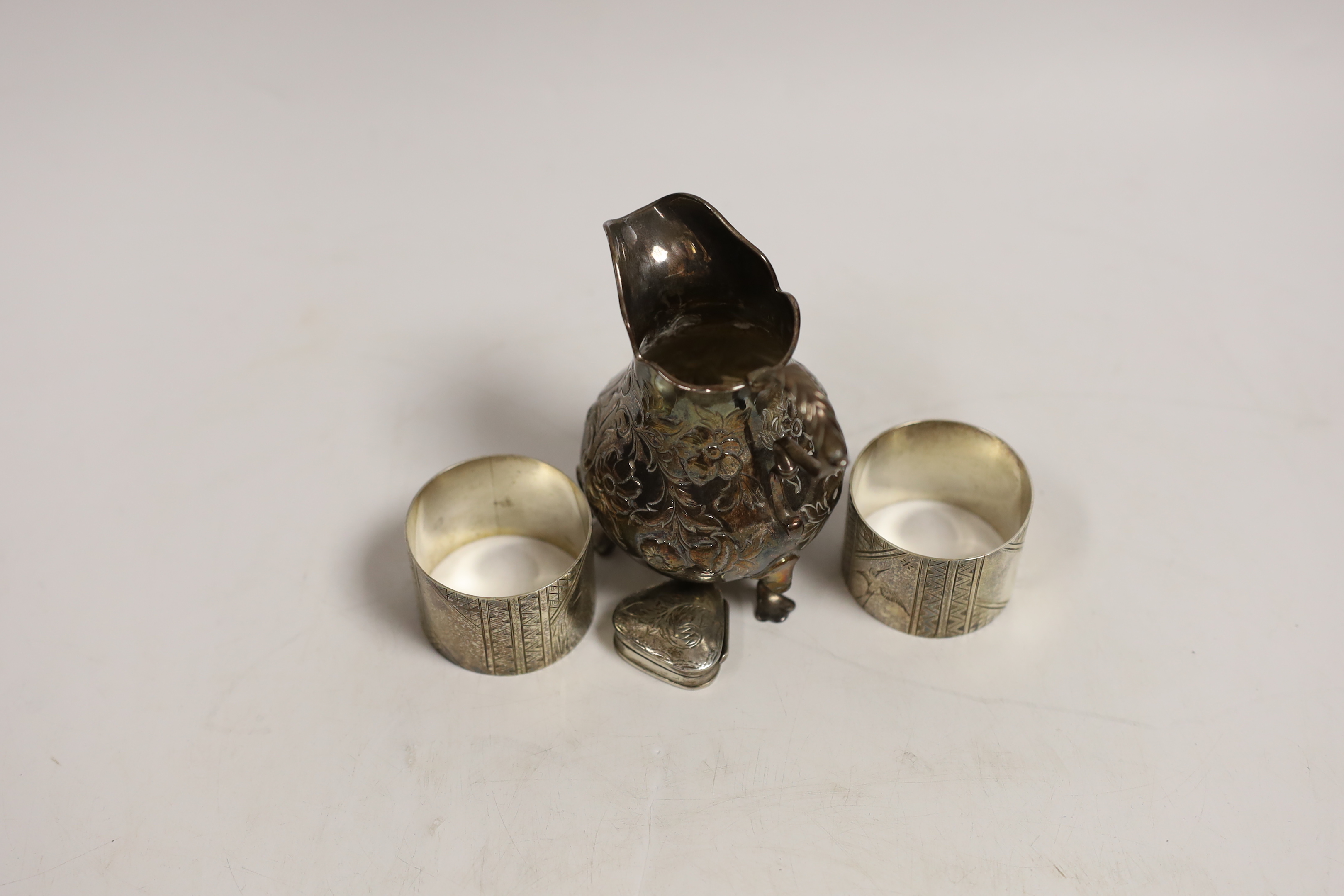 A Victorian silver baluster cream jug, London, 1846, 95mm, a pair of Victorian silver napkin rings engraved with aesthetic decoration, Charles Edwards, London, 1880 and a modern silver pill box.